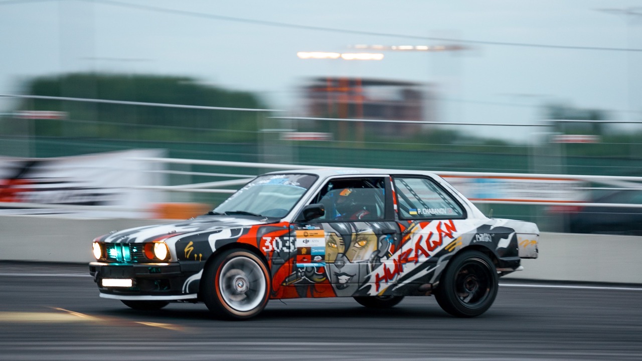 Motorsport documentary still — a drift car sliding through a corner at speed